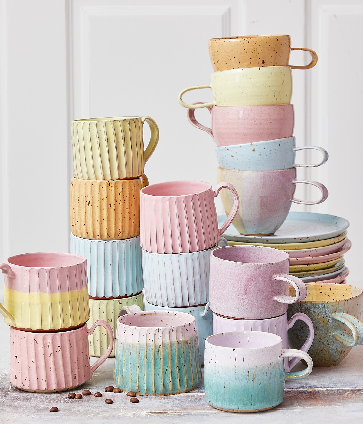 Keramikbecher und Tassen mit Griffen und Tassen ohne sie, rosa Keramikbecher, Karamellbecher in Pastell.